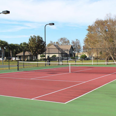 Tennis court with trees and buildings in the background