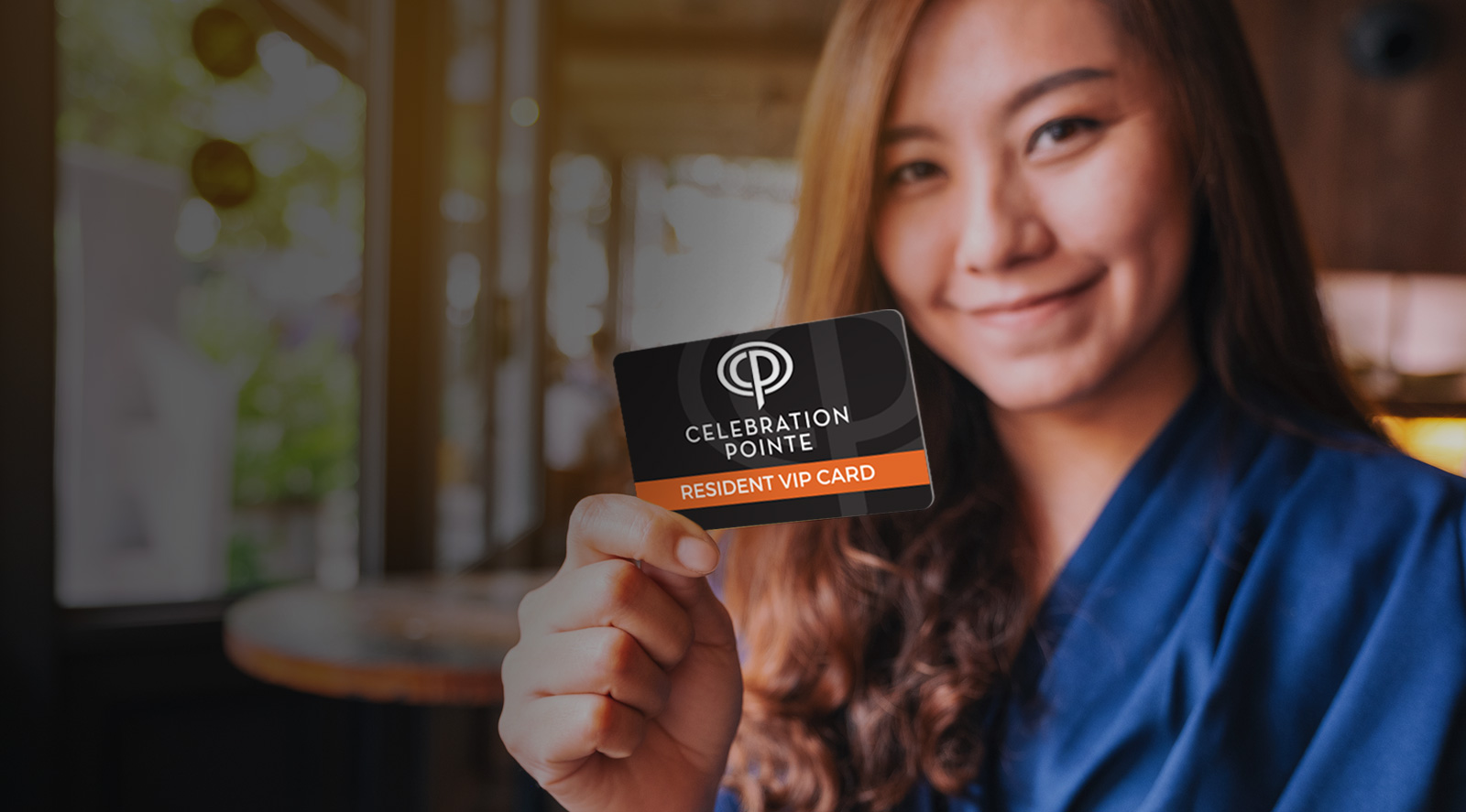 young woman smiling and holding a Celebration Pointe Resident VIP Card